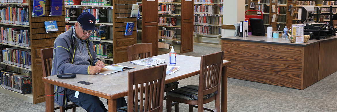 Man sitting at one of the tables in the adult services area of the library