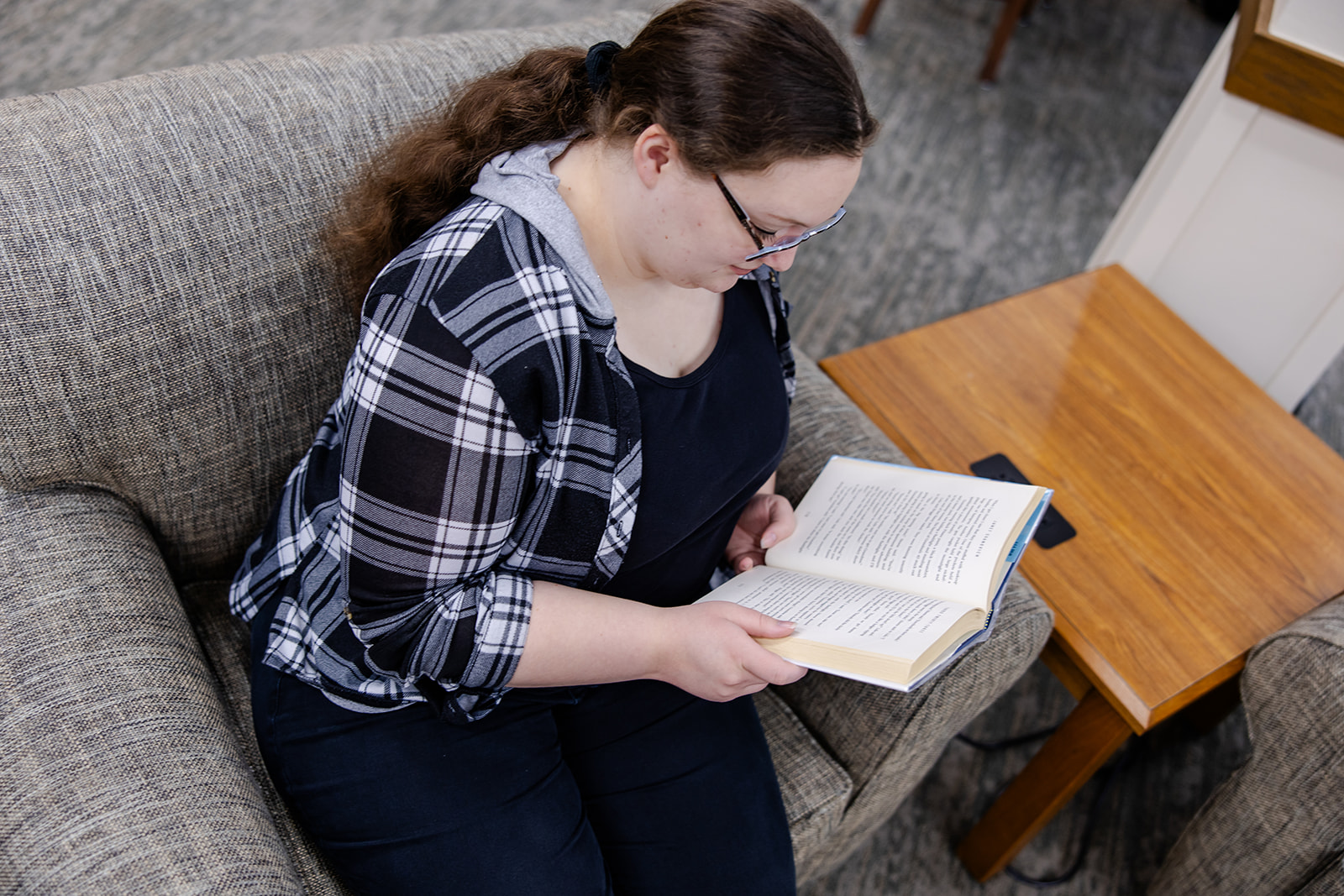 Circulation librarian Mary reading on a grey chair