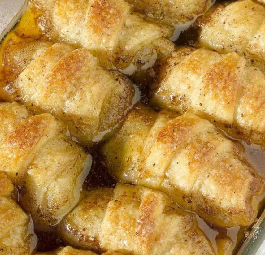 Two rows of fresh-baked apple dumplings in a pan. 