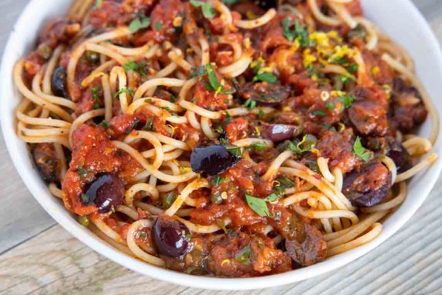 A close-up look at pasta puttanesca, a tomato-based pasta dish. 