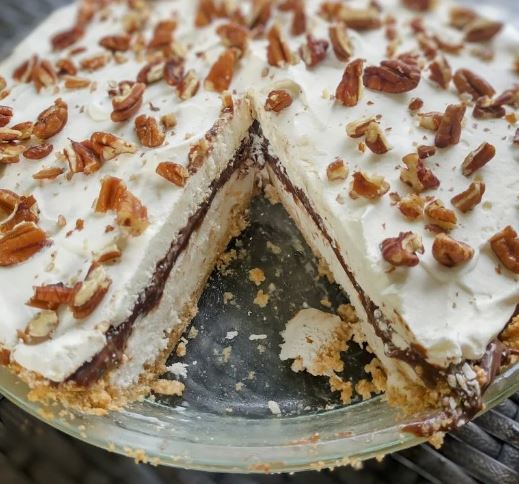 A close-up look at a chocolate sundae pie, with one slice removed to reveal the chocolate filling. 