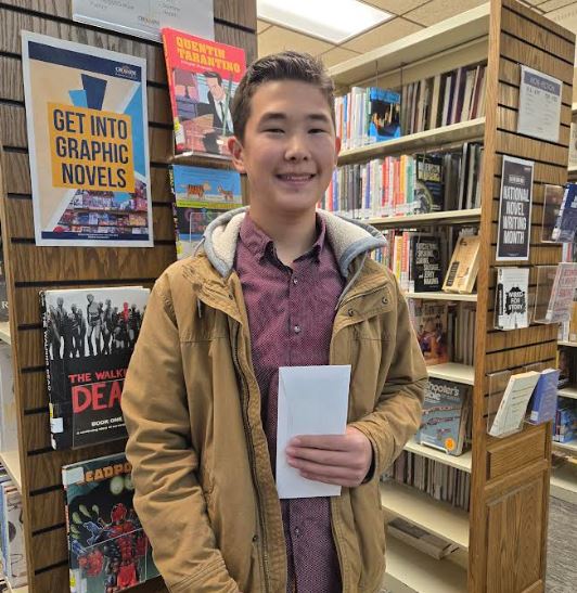 Andrew in the Library, holding his award for the Grant Sweet Contest. 