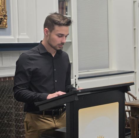 Gabriel Bliss reading his Grant Sweet Essay aloud at the podium in the Community Room. 