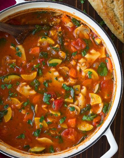 A pot of vegetable lasagna soup on a wooden table. 