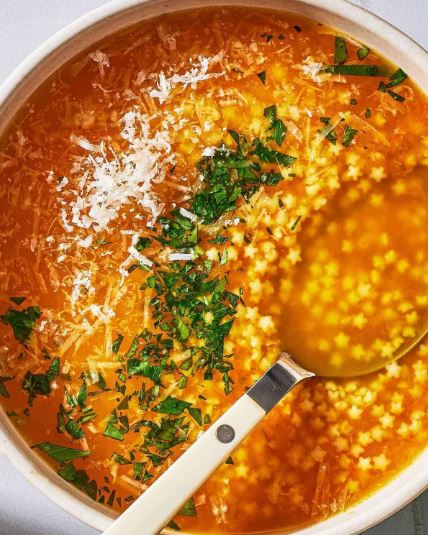 A bowl of pastina soup, featuring small star-shaped pasta, fresh parsley, and sprinkled parmesan. 