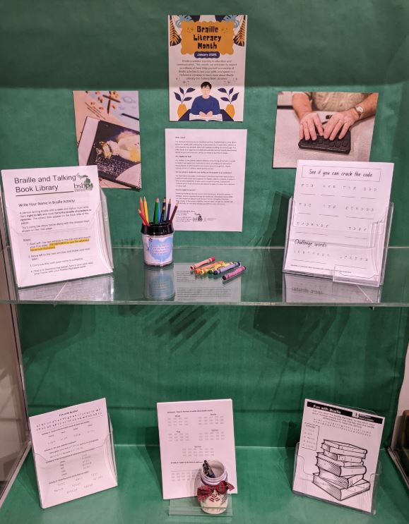 The first floor display case featuring a green background, information on Braille, and multiple worksheets to test your braille reading skills. 