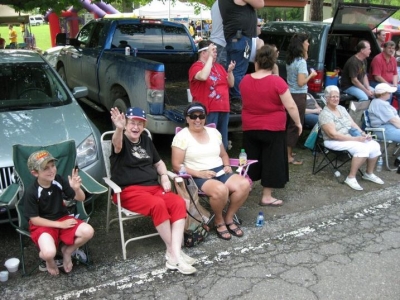 Hartland residents smiling and waving while sitting in lawn chairs at the Memorial Day parade