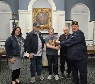 Ryan Schlosser shaking hands with Doug Kuhn, with Ryan's grandfather, Liz, and local veteran Robert Gauthier, Sr.