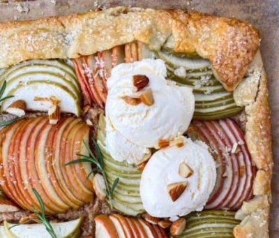 Above-shot of an apple galette with a thick corner crust and ice cream dollop on top.