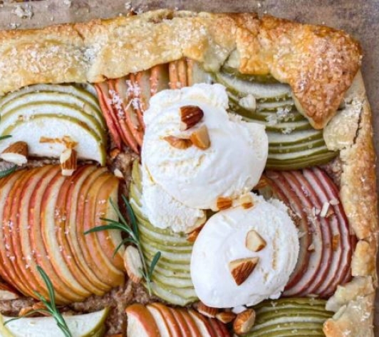 Above-shot of an apple galette with a thick corner crust and ice cream dollop on top.