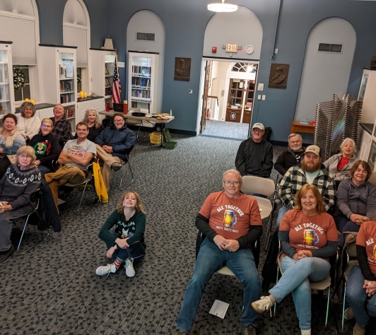 The Ale Together Now crew sitting in the Community Room, with Michelle sitting in the middle of the aisle.