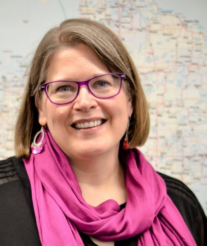 Presenter wearing pink scarf and glasses