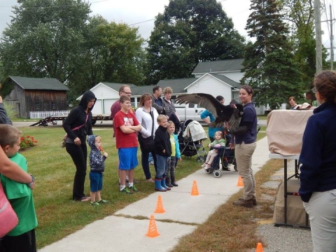 A representative from Howell Nature Center holding a vulture on the South Lawn, surrounded by an audience of children. 