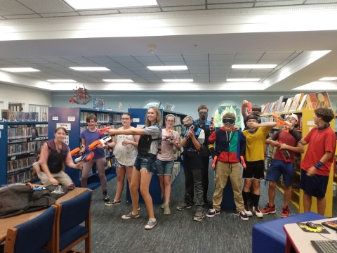 Teens posing with nerf guns in the Youth Department. 