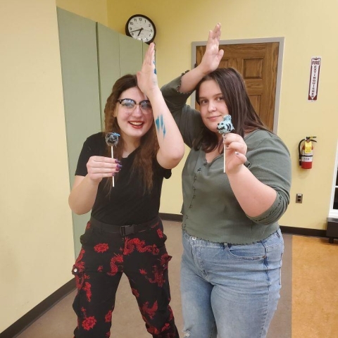 Tweens holding up their decorated cake pops in the Youth Program Room. 