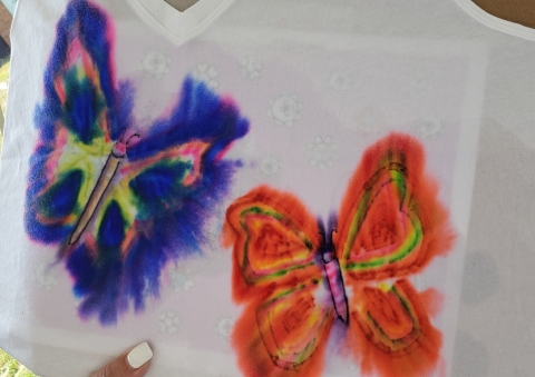 A tie-dye shirt, with a drawn-on butterfly design. 