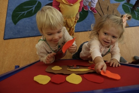 Two toddlers pinning felt leaves to a board during storytime in the Youth Program Room. 