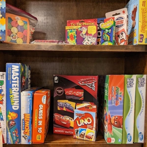 A variety of board games, puzzles, and card games on a shelf at Cromaine Library. 