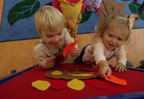 Two toddlers pinning felt leaves to a board during storytime in the Youth Program Room. 