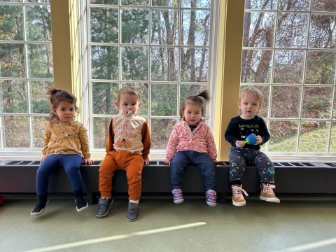 Children sitting in front of the Youth Program Room windows. 