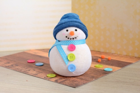 A sock snowman with red, green, and blue buttons with a blue hat and scarf. 