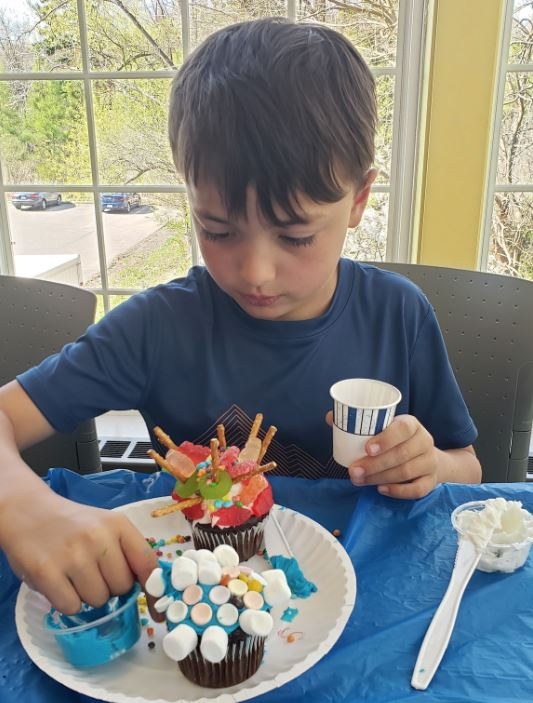 An elementary-aged attendee decorates a cupcake at a Cupcake Wars program. 