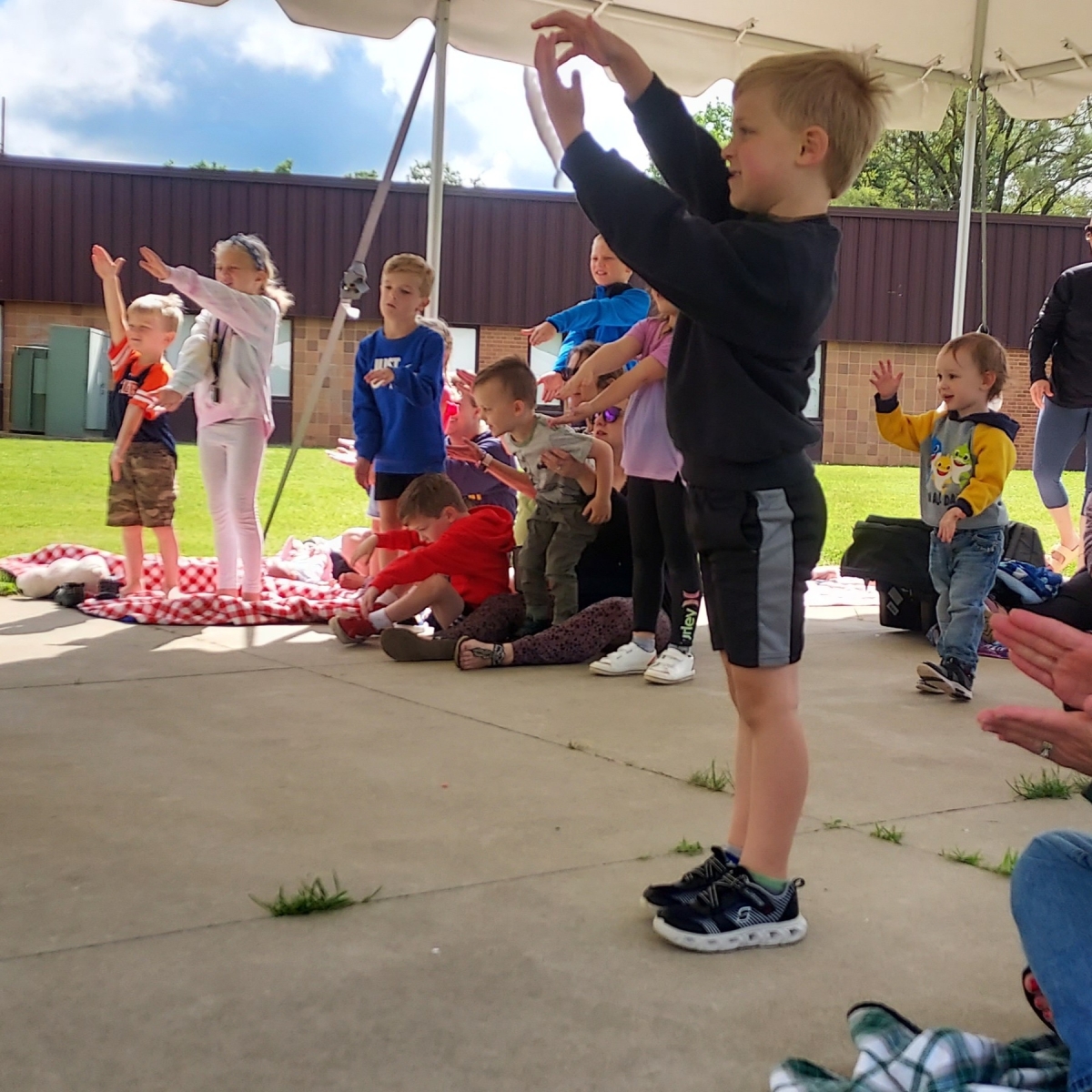 Children standing under the South Lawn tent, engaging with a storytime event. 