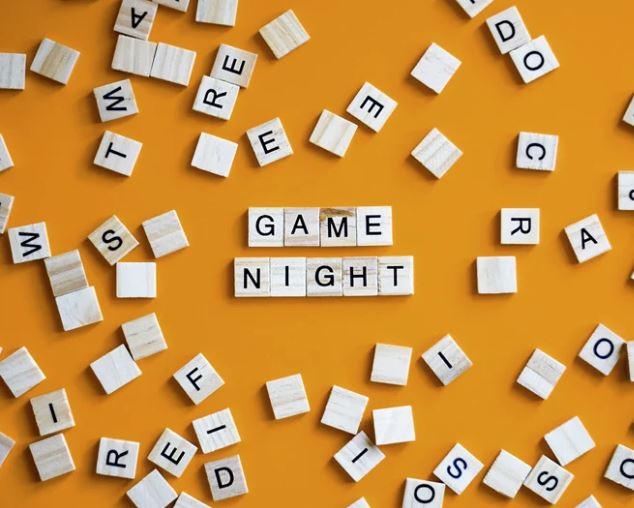 "Game Night" spelled out with letter game pieces, with other pieces around it. 