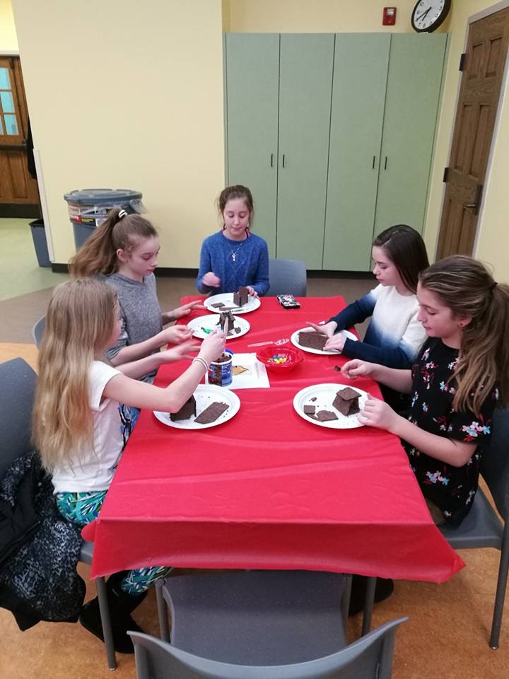 Teens seated at a table with plates of dessert. 