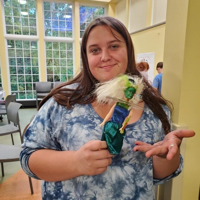 A tween holding a zombie Barbie doll that she made in the Youth Program Room. 