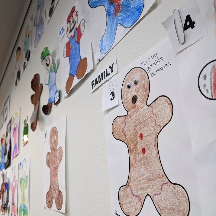 A variety of gingerbread people, colored in and drawn on, hung on the wall at the Library. 